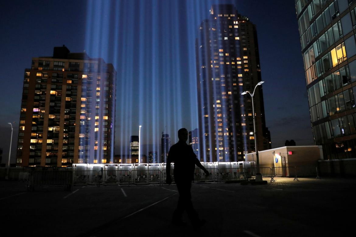 Un hombre camina por el Tributo a la Luz, iluminado para conmemorar el 18 aniversario del ataque del 11 de septiembre de 2001 en la ciudad de Nueva York, REUTERS