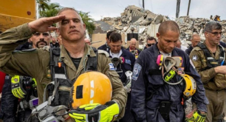 Miembros de un equipo de búsqueda y rescate durante momento de silencio frente a los escombros en Champlain Towers South.