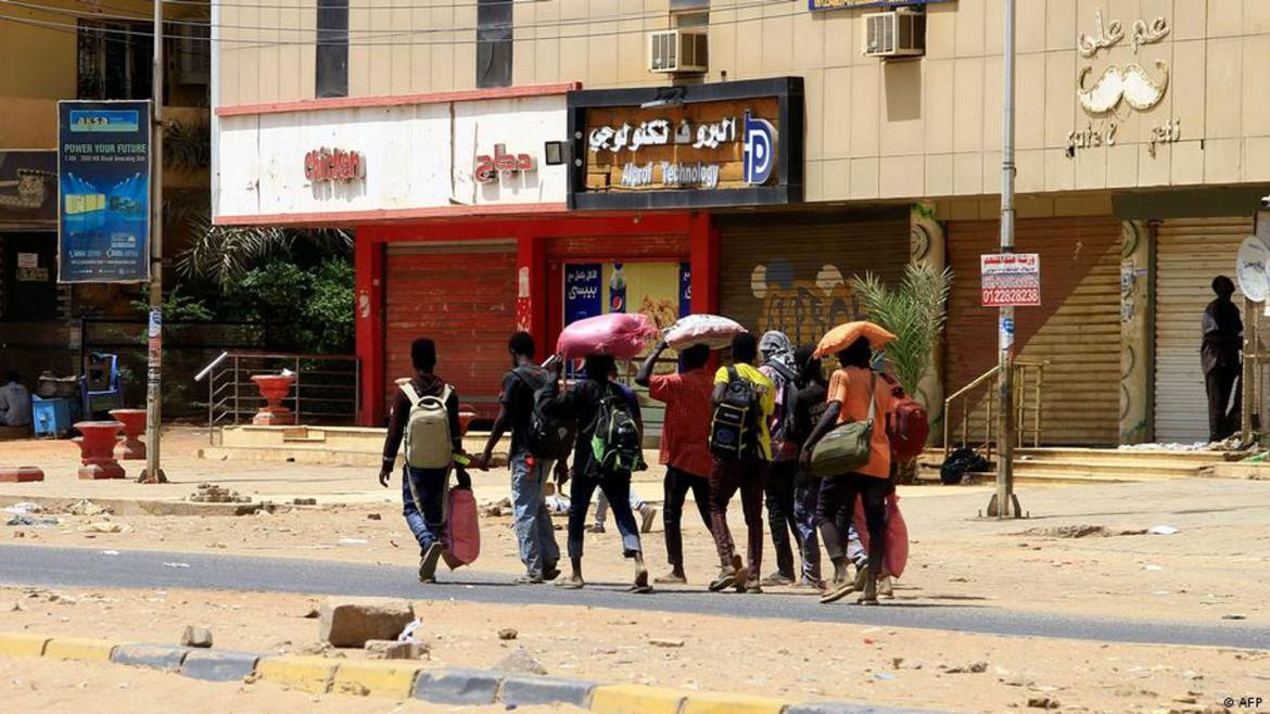 Civiles caminan con sus pertenencias por Jartum. Foto: AFP