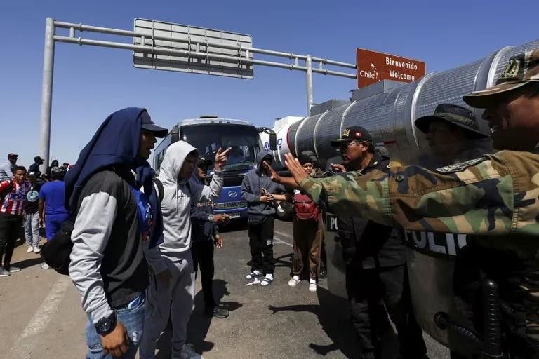 Migrantes indocumentados, en su mayoría de Venezuela, Colombia y Haití, hablan con policías peruanos. Foto: Reuters