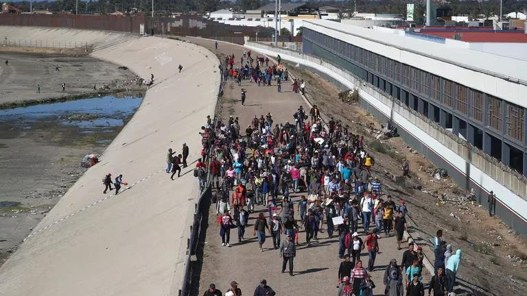 Migrantes caminan por Tijuana a un costado de la valla fronteriza entre México y Estados Unidos. Foto: Reuters