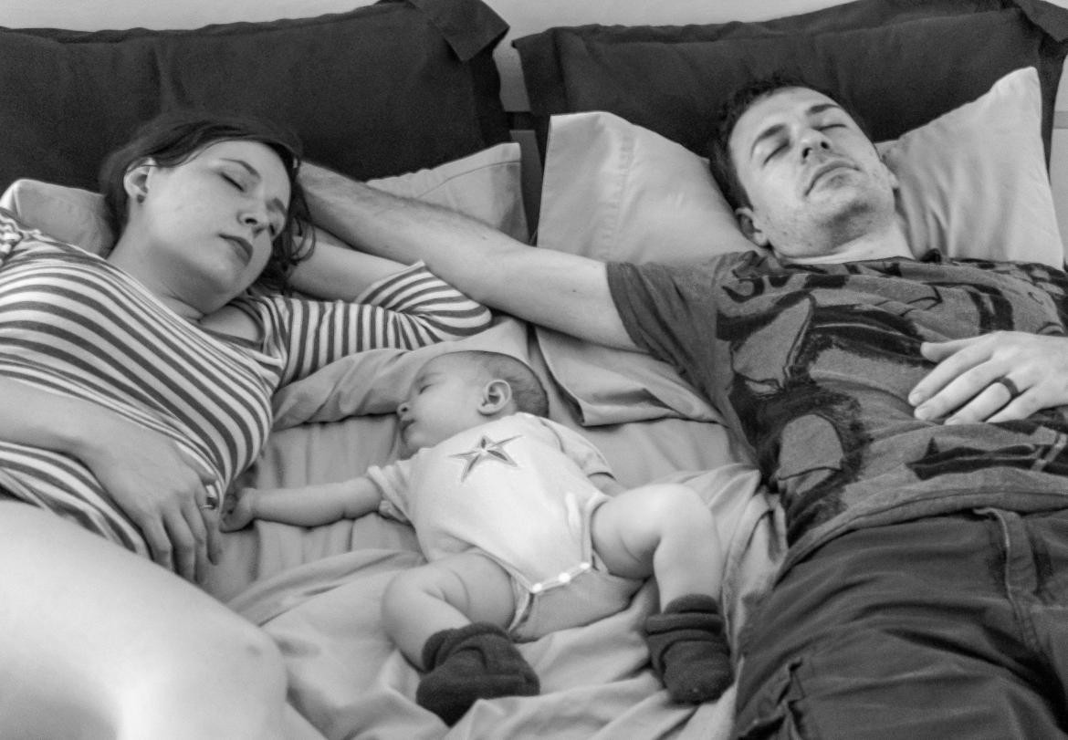 Bebé durmiendo junto a sus padres; síndrome de muerte súbita del lactante. Foto: Unsplash.