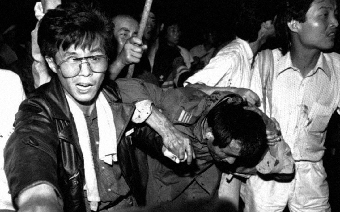 Los estudiantes ayudan a un conductor de tanque capturado a ponerse a salvo mientras la multitud lo golpea, el 4 de junio de 1989. Foto: Reuters.