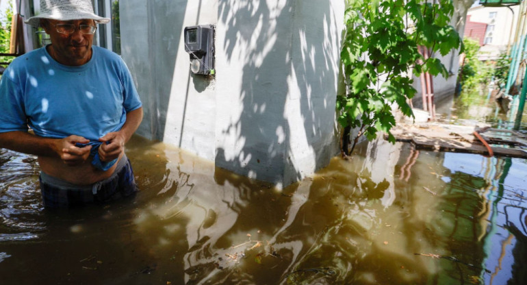 Un vecino camina por el patio de su vivienda inundada en la ciudad de Nova Kajovka, en la región de Jersón. Fuente: Reuters.