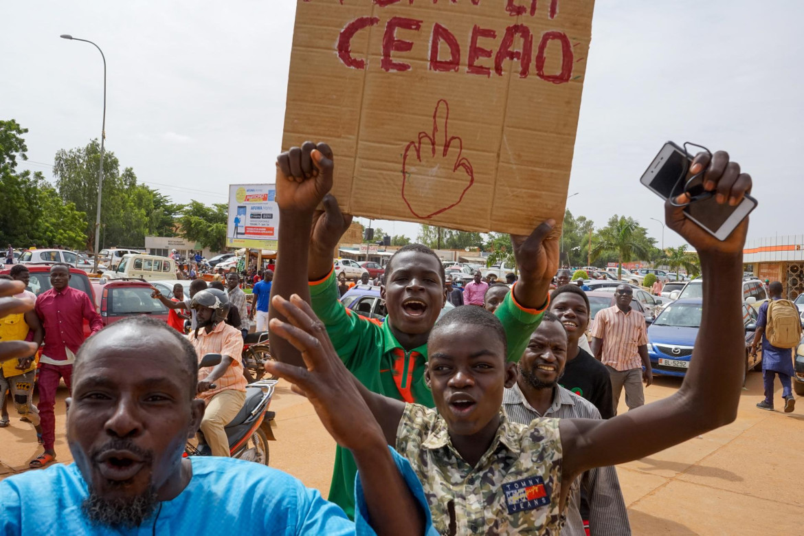 La gente agita una pancarta mientras se dirige a un mitin en un estadio en Niamey. Foto Reuters