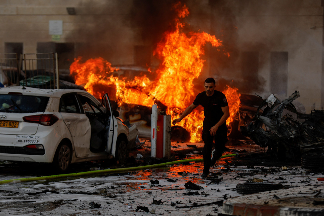 Un hombre corriendo mientras un auto se incendia tras un ataque lanzado desde la Franja de Gaza, en Ashkelon, Israel. Foto: Reuters