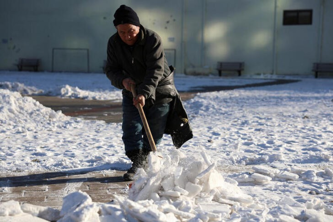 Ciudadana china quitando la nueve de la entrada de su casa en Pekín. Foto: Reuters.