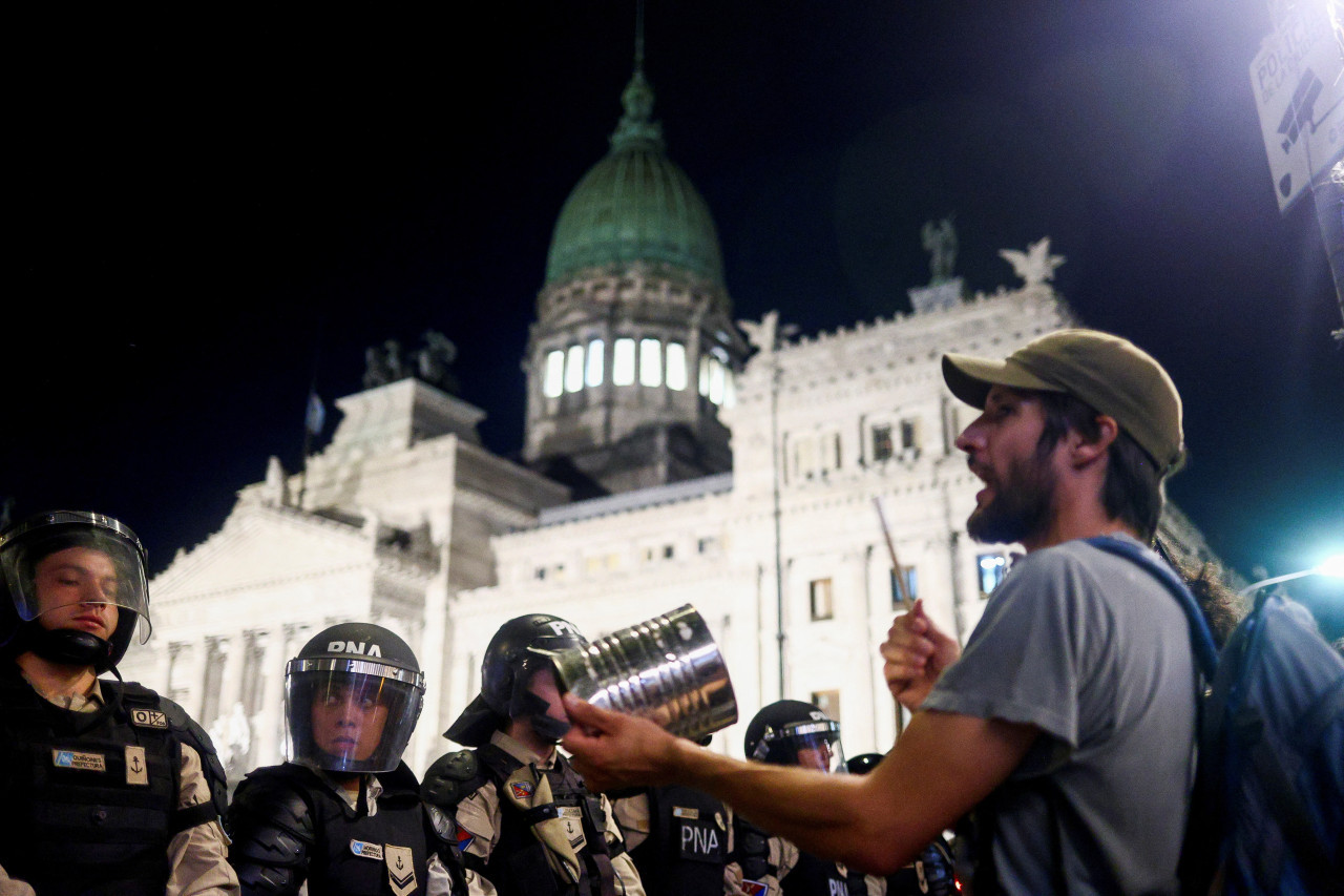 Manifestante golpea una cacerola frente al Congreso de la Nación durante la votación de la ley Ómnibus. Foto: Reuters.