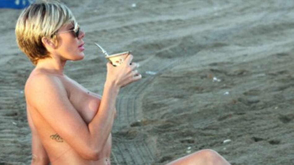 Diosa toma mate desnuda en la playa
