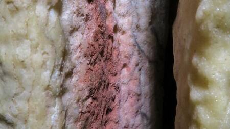 Marcas rojas encontradas en una estalagmita en la caverna de Ardales (en Málaga, España), que podrían ser las pinturas rupestres más antiguas del mundo conocidas hasta ahora. Imagen cedida por la Universidad de Cádiz.