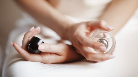 Bride holds a bottle of parfume in her tender arms