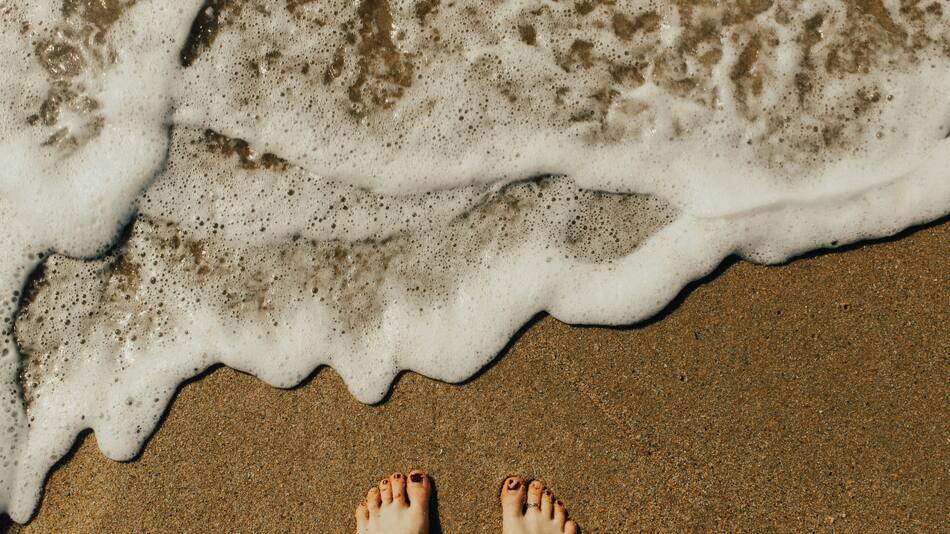 Los pies se ensucian en la playa. Foto: Unsplash.