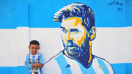 En Bangladesh. Un niño posa en la calle junto a un retrato graffiti de su ídolo, Lionel Messi. Foto Reuters