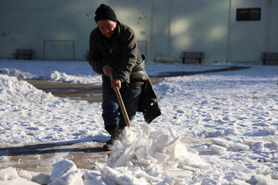 Ciudadana china quitando la nueve de la entrada de su casa en Pekín. Foto: Reuters.