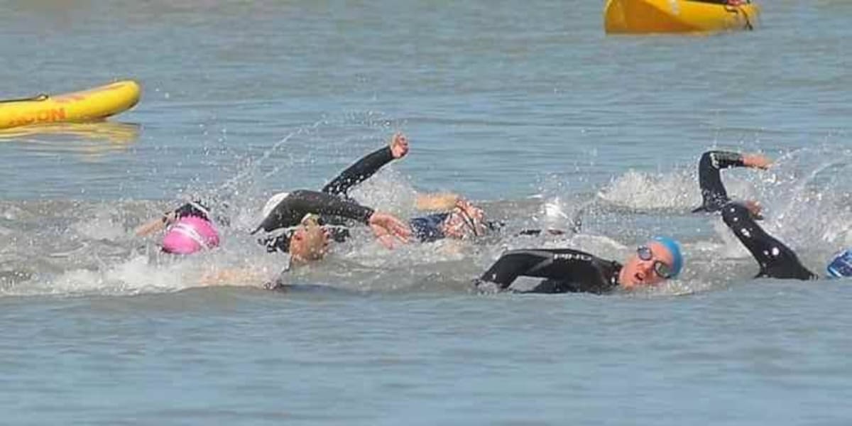 Nadadores compiten en una prueba de aguas abiertas en el mar durante un evento deportivo.