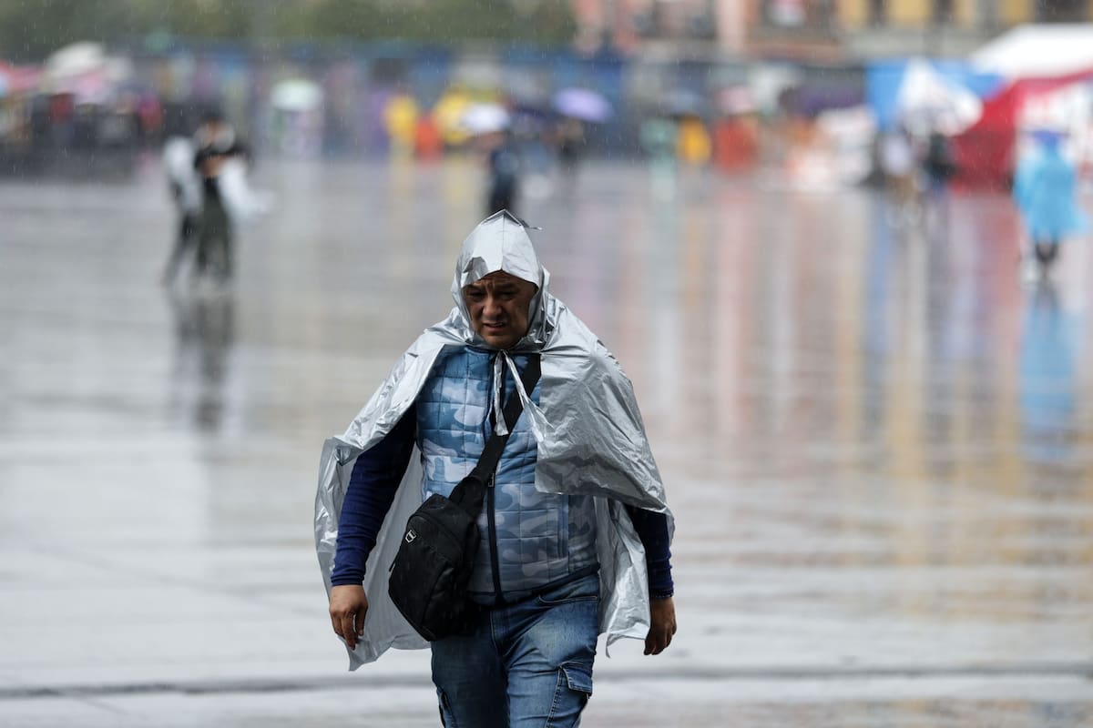 Personas usando piloto caminan bajo la lluvia.