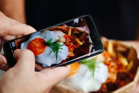 Comer con el celular, una práctica poco recomendable. Foto: Unsplash.