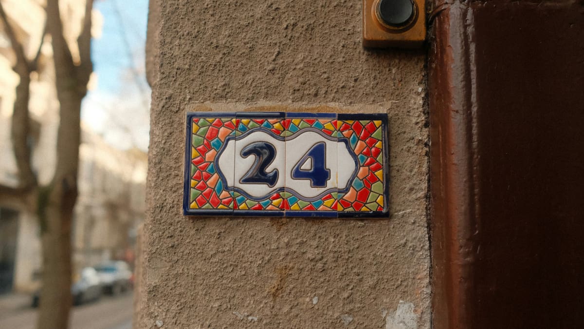 Una casa decorativa de cerámica número 24 sobre una pared texturizada.