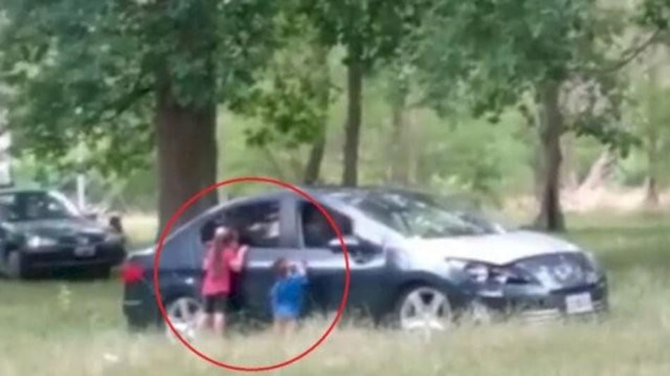 Niños fuera de un auto con sus padres dentro en el Parque Pereyra Iraola