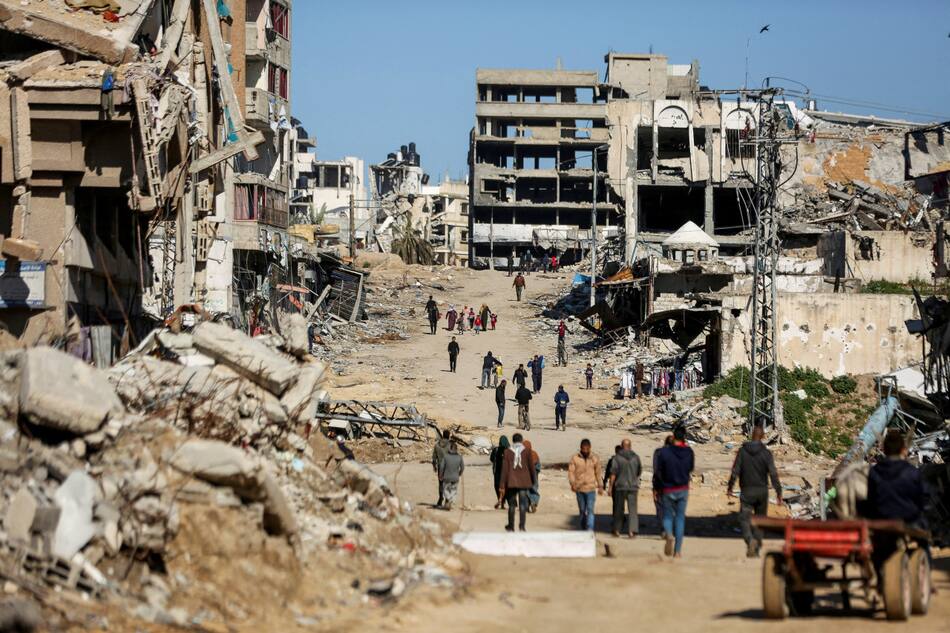 Palestinos caminan junto a las ruinas de las casas destruidas durante la ofensiva militar de Israel. Reuters