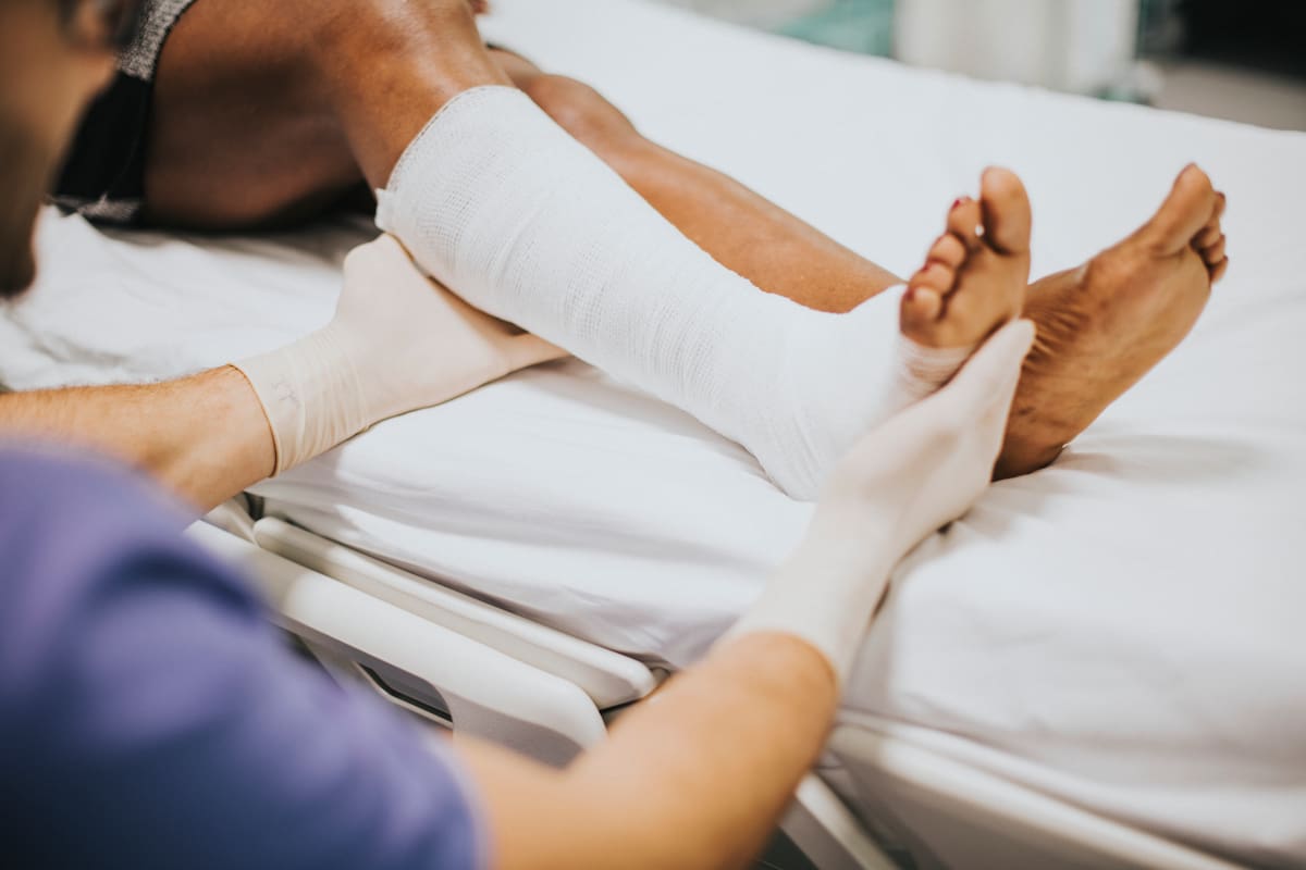 Médico atendiendo a un paciente con una pierna fracturada.