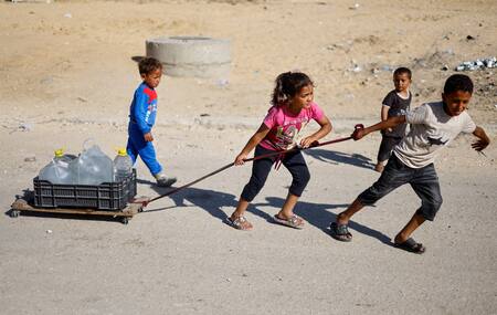 Niños palestinos llevan agua al evacuar Rafah. Foto: Reuters