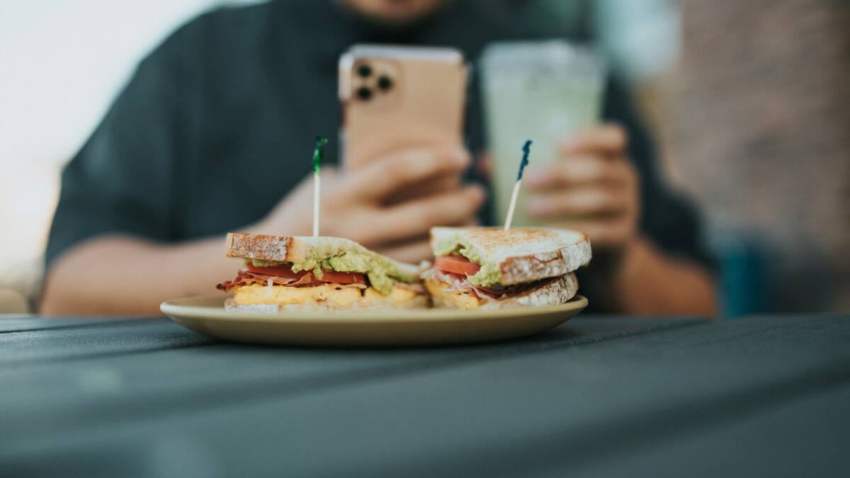 Comer con el celular, una práctica poco recomendable. Foto: Unsplash.
