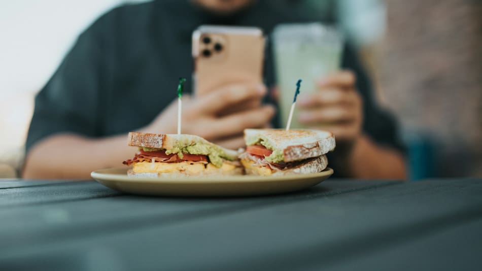 Comer con el celular, una práctica poco recomendable. Foto: Unsplash.