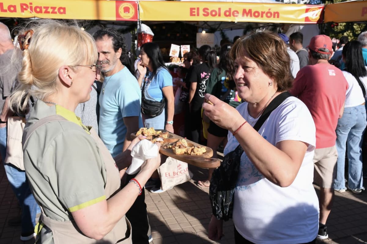 Trabajadora ofrece pan dulce a una vecina en Morón durante el Pan Dulce de Oro.