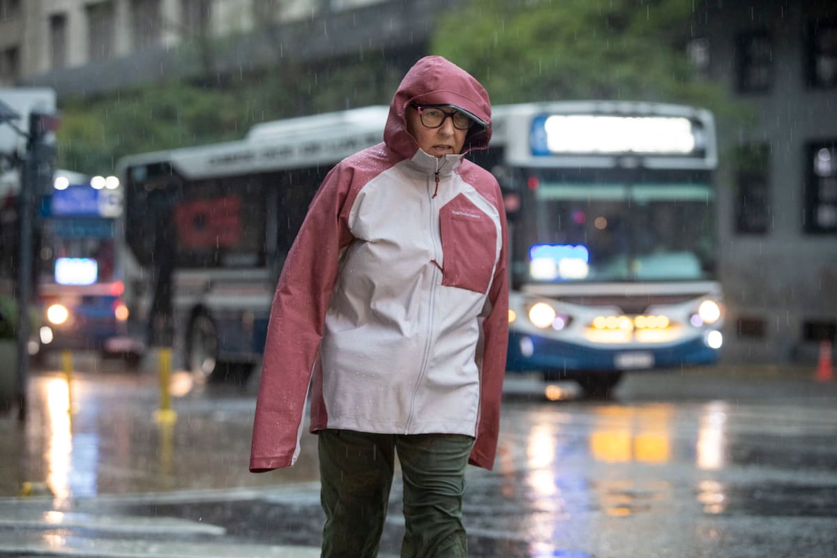 Una mujer se resguarda de la lluvia y el frío en las calles de Buenos Aires.