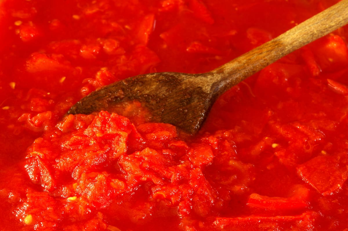 Cuchara de madera revolviendo salsa de tomate.