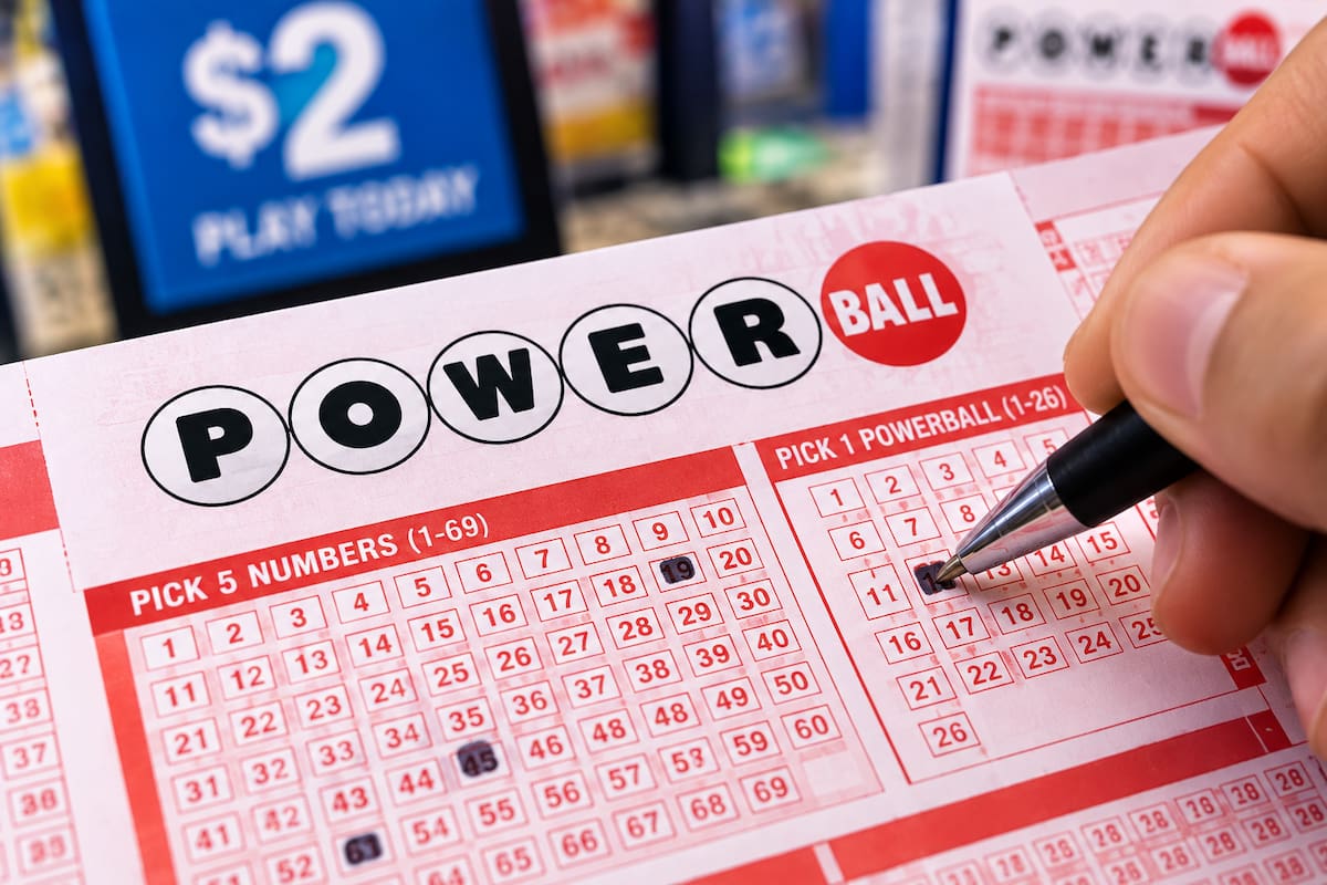 Boleto de Powerball con números seleccionados y una persona marcando la combinación para participar en la lotería de Estados Unidos.