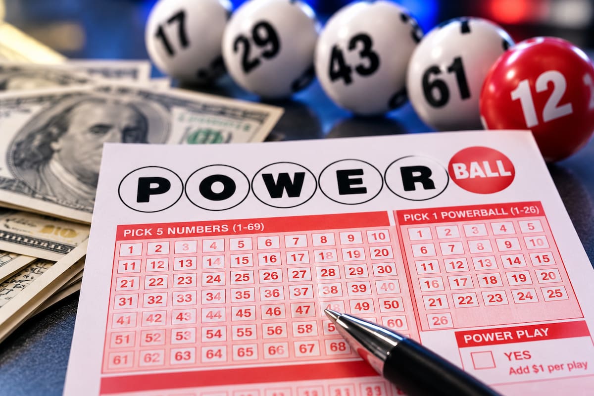 Boleto de Powerball con números seleccionados y una persona marcando la combinación para participar en la lotería de Estados Unidos.