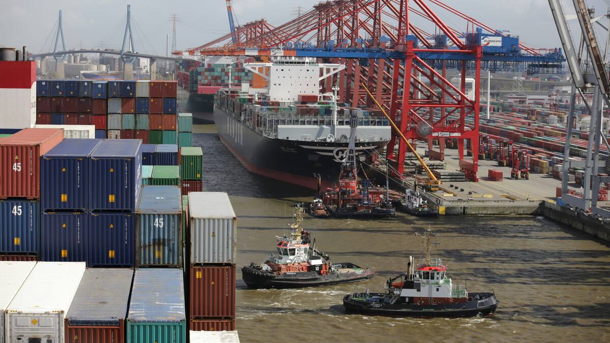 Barcos navegan por un astillero alrededor de containers.