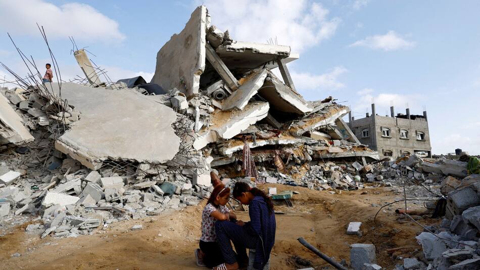 Niños palestinos sentados junto al lugar de un ataque israelí contra una casa. Foto: Reuters