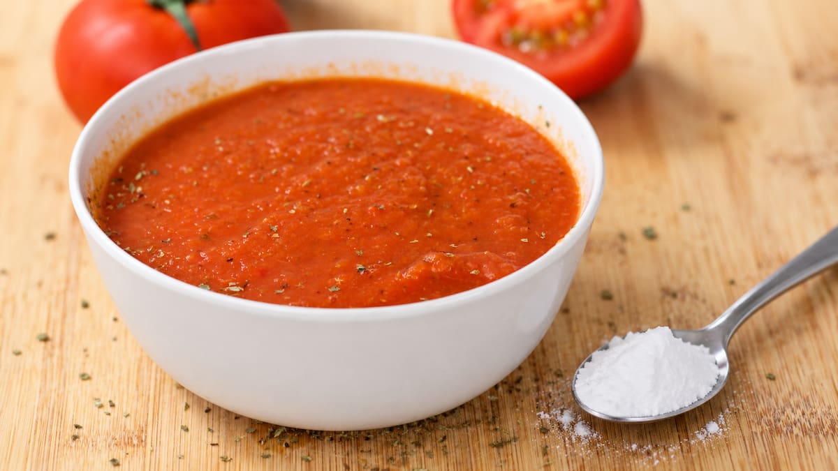 Tazón de salsa de tomate junto a una cucharadita de bicarbonato de sodio.