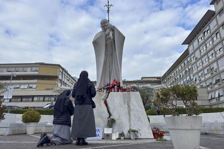 Velas y flores a los pies de la escultura de Juan Pablo II a las puertas del Hospital Gemelli de Roma donde permanece ingresado el papa Francisco. EFE