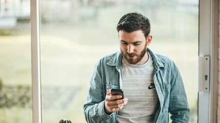 Hombre usando celular. Unplash