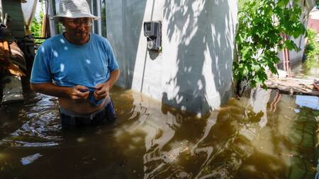 Un vecino camina por el patio de su vivienda inundada en la ciudad de Nova Kajovka, en la región de Jersón. Fuente: Reuters.