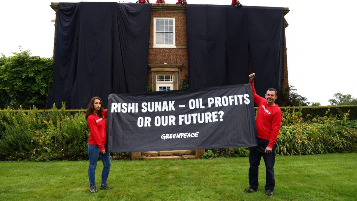 Activistas de Greenpeace sostienen una bandera mientras otros cubren la casa de verano del primer ministro británico. Foto: Reuters.