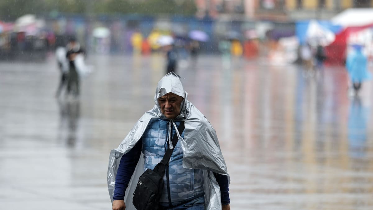 Personas usando piloto caminan bajo la lluvia.