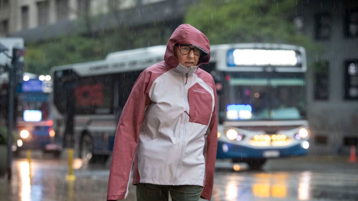 Una mujer se resguarda de la lluvia y el frío en las calles de Buenos Aires.
