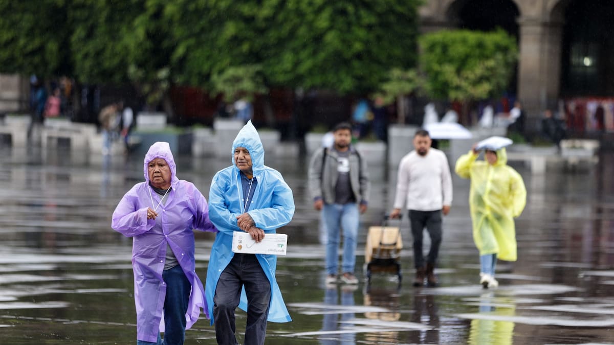 Personas usando piloto caminan bajo la lluvia.