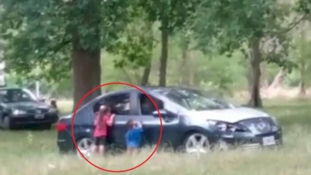 Niños fuera de un auto con sus padres dentro en el Parque Pereyra Iraola