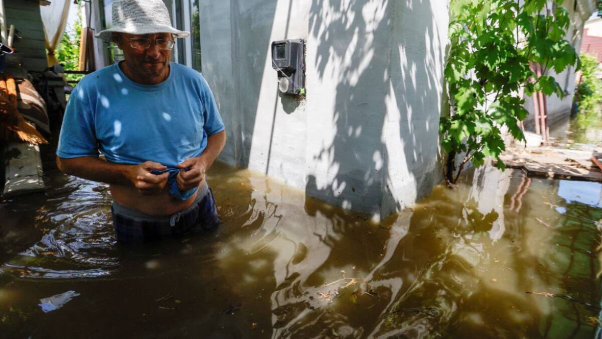Un vecino camina por el patio de su vivienda inundada en la ciudad de Nova Kajovka, en la región de Jersón. Fuente: Reuters.