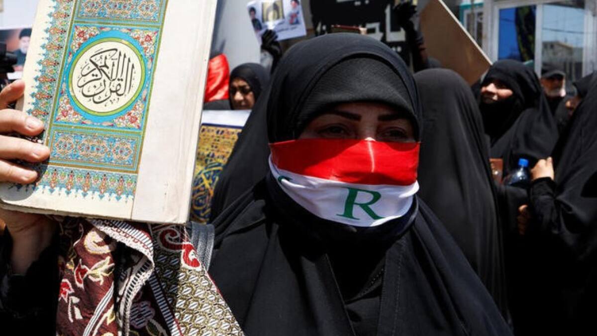 Una mujer muestra un Corán durante una protesta. Foto: Reuters.