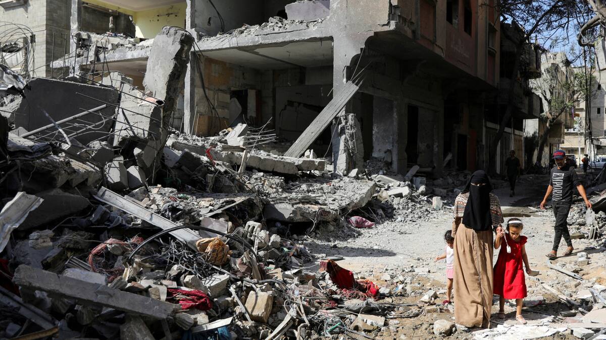 Una mujer y un niño caminan entre escombros tras ataques israelíes en Gaza. Foto: Reuters